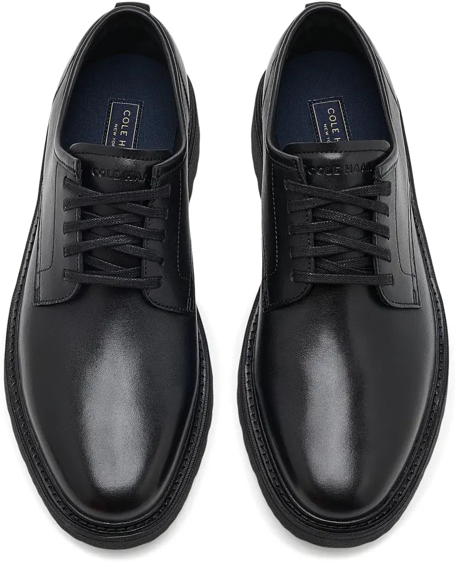 A pair of black leather lace-up dress shoes with a chunky black sole, shown from a top-down view on a white background.