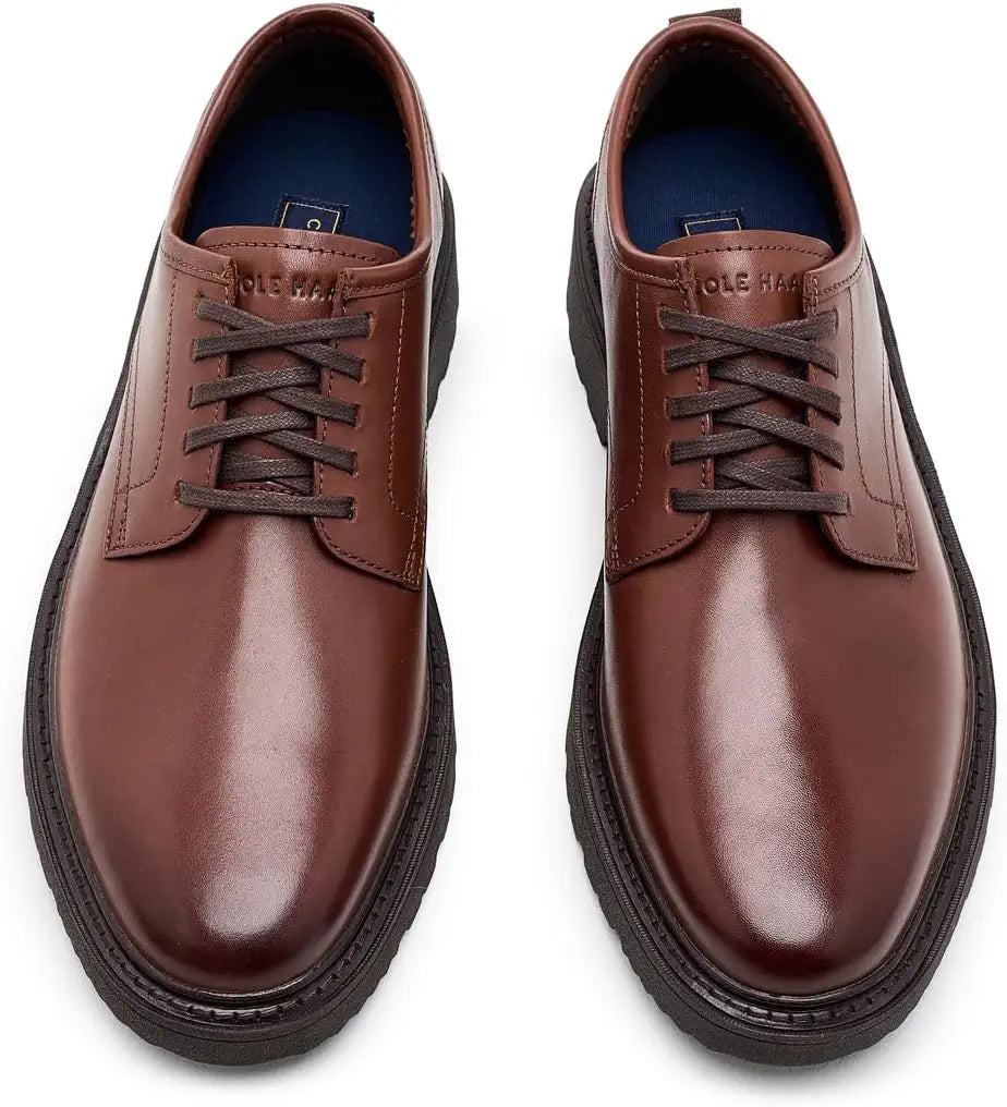 A pair of men's brown leather lace-up shoes with dark brown laces and thick black soles, shown from a top-down perspective on a white background.