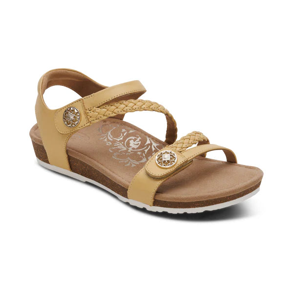 Beige sandal with braided design and decorative buttons on a white background