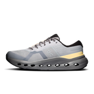 A light gray and white On running shoe with a black heel tab, gray laces, a yellow accent stripe, and a dark gray sole with cutout details, shown from a side profile on a white background.