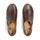 A pair of dark brown leather slip-on shoes shown from a top-down view on a white background. The brand name 'taos' is printed on the tan insoles with a black floral pattern.
