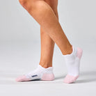 White ankle socks with pink toes worn by a person on a light gray background