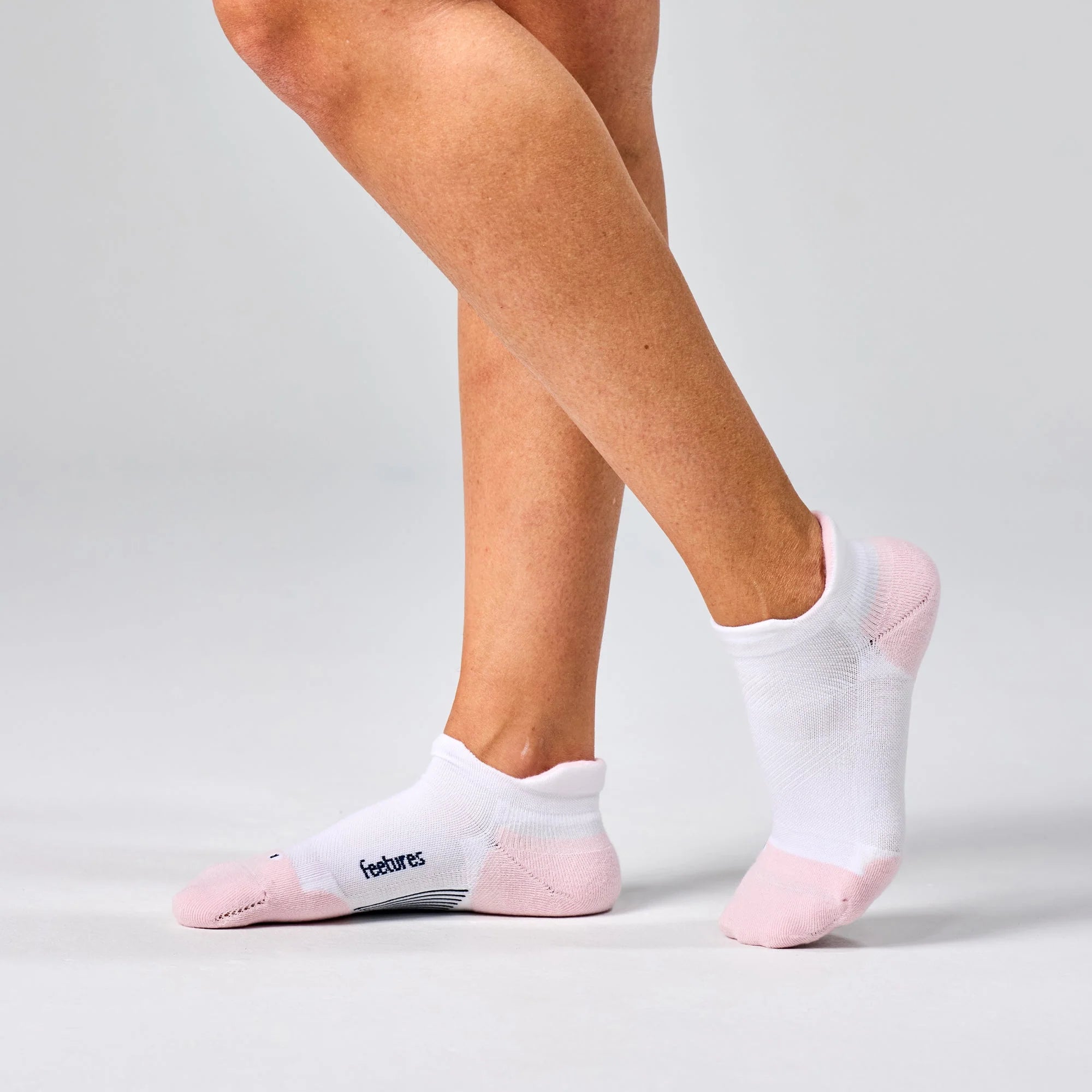 White ankle socks with pink toes worn by a person on a light gray background