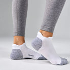 White ankle socks with gray accents worn with gray leggings on a light gray background