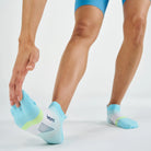 Light blue ankle socks with green accents worn by a person on a white background