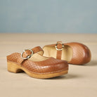Brown clogs with wooden sole on a beige surface