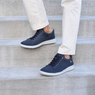 Navy blue sneakers with white soles worn by a person on concrete steps.