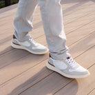 Light gray sneakers with white soles worn on a wooden deck