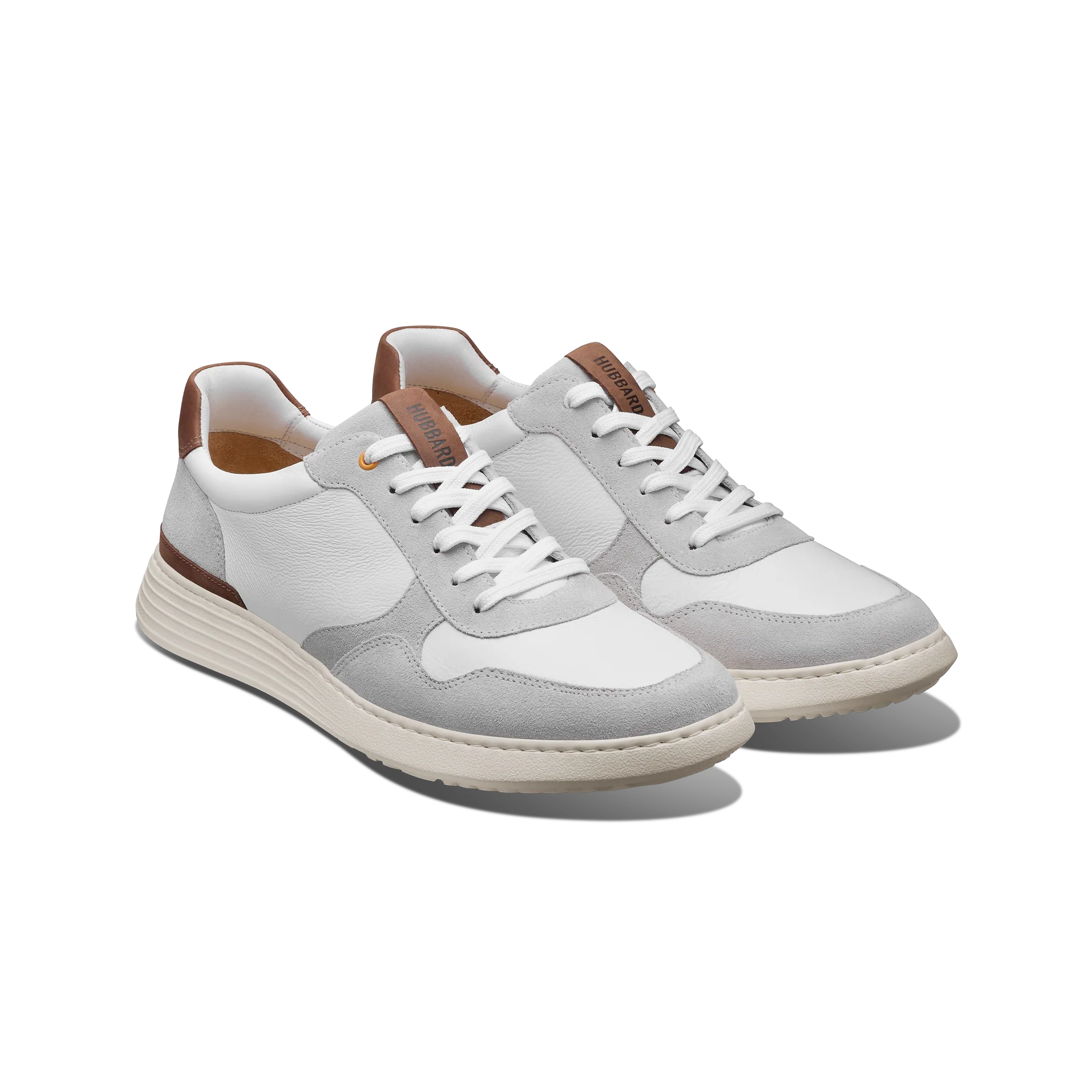 Pair of white sneakers with brown accents on a white background