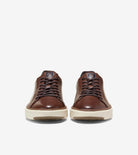 A pair of brown leather low-top sneakers shown from the front on a light gray background.