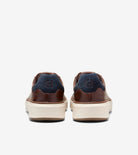 A pair of low-top sneakers shown from the back, featuring dark brown leather and navy blue suede panels on a light beige platform sole.