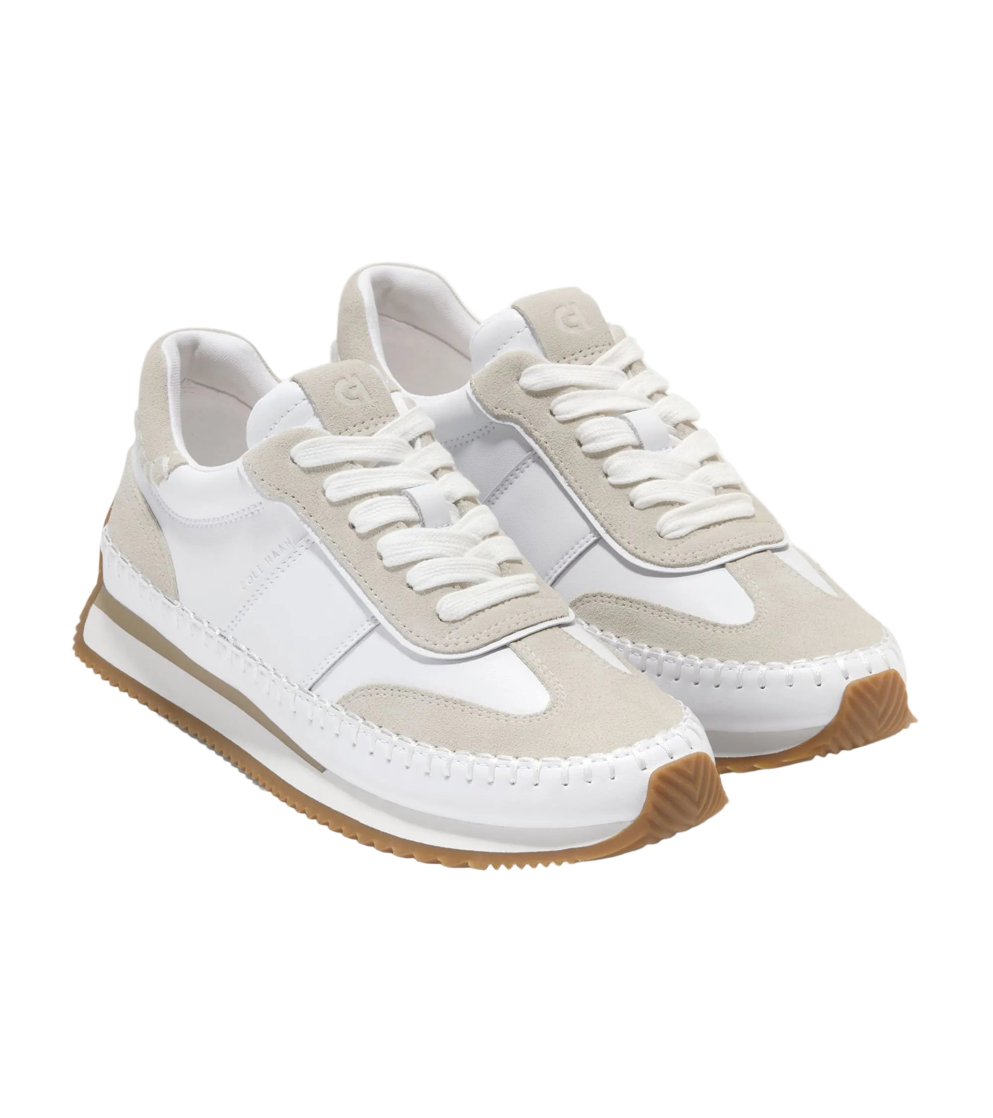 White and beige sneakers with brown soles on a light gray background