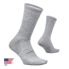 A pair of light gray heather crew socks shown on a clean off-white background, with one sock standing upright and the other lying on its side. A small 'Made in the USA' flag graphic appears in the bottom-left corner.