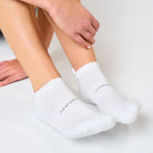 White ankle socks worn by a person on a light gray background