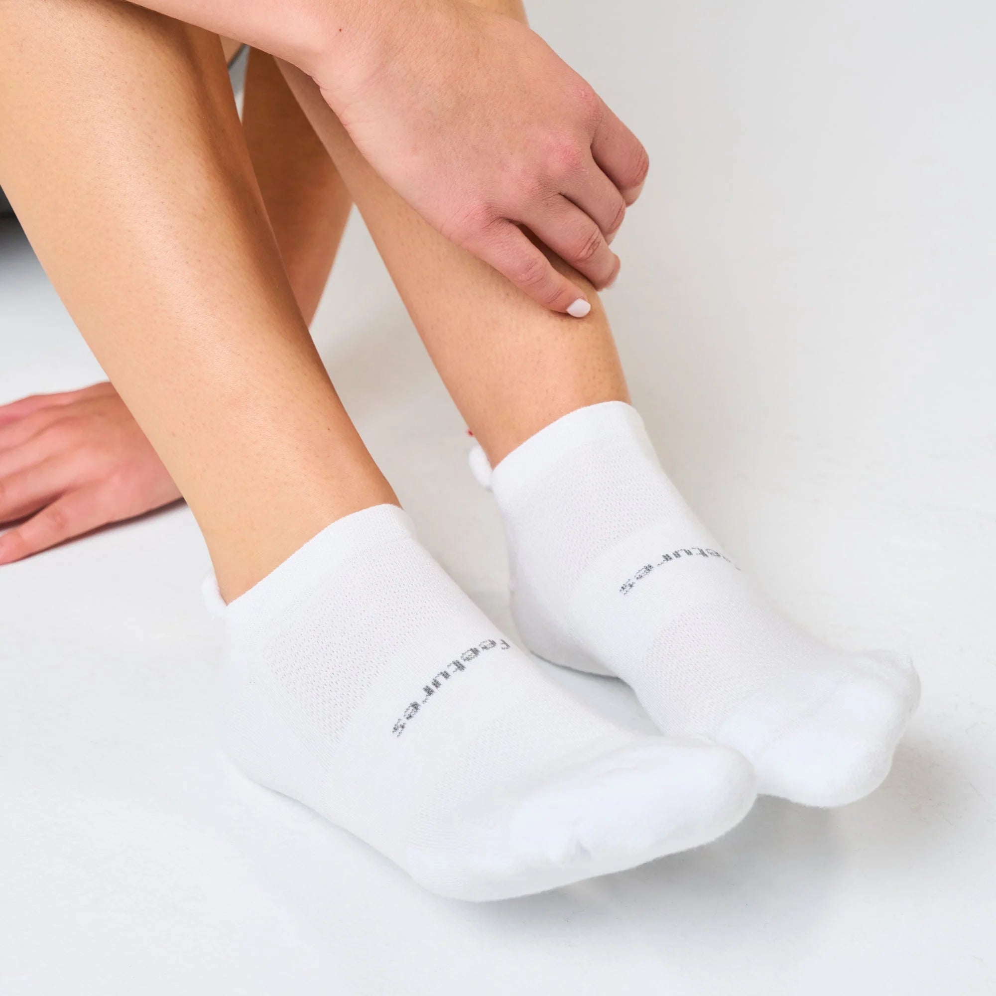 White ankle socks worn by a person on a light gray background