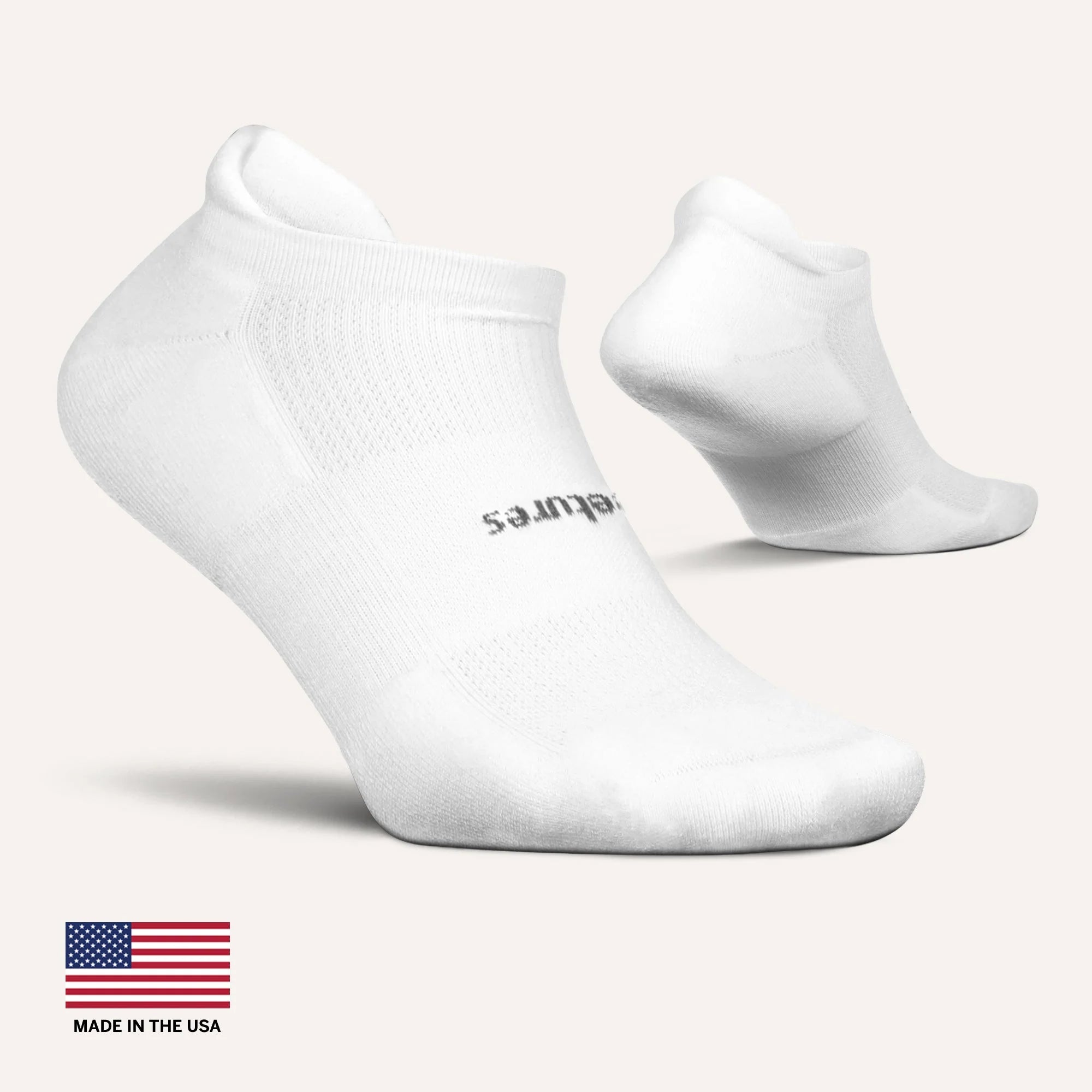 Two white socks with a brand logo on a light gray background, featuring 'Made in the USA' text.