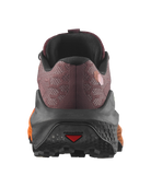 A rear view of a trail running shoe on a plain white background. The shoe features a textured burgundy mesh upper, a thick black midsole, and bright orange accents on the sides and outsole, with a small red triangular logo on the rear of the sole.