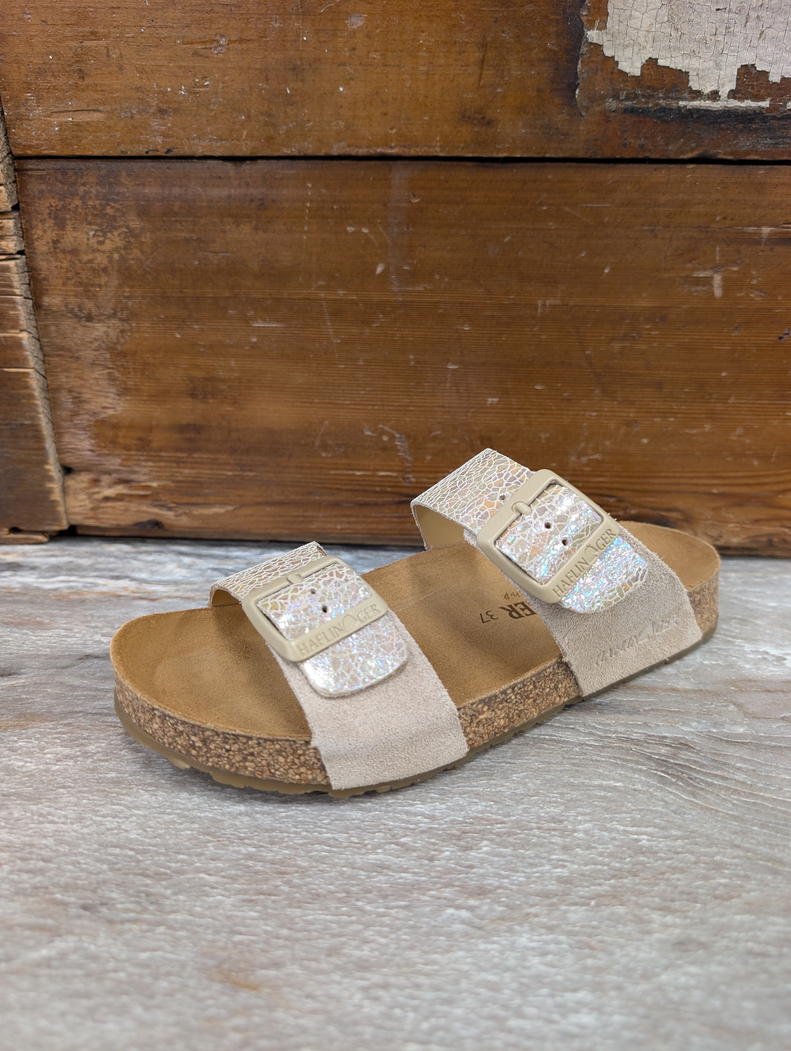 Beige sandals with glittery straps on a wooden surface