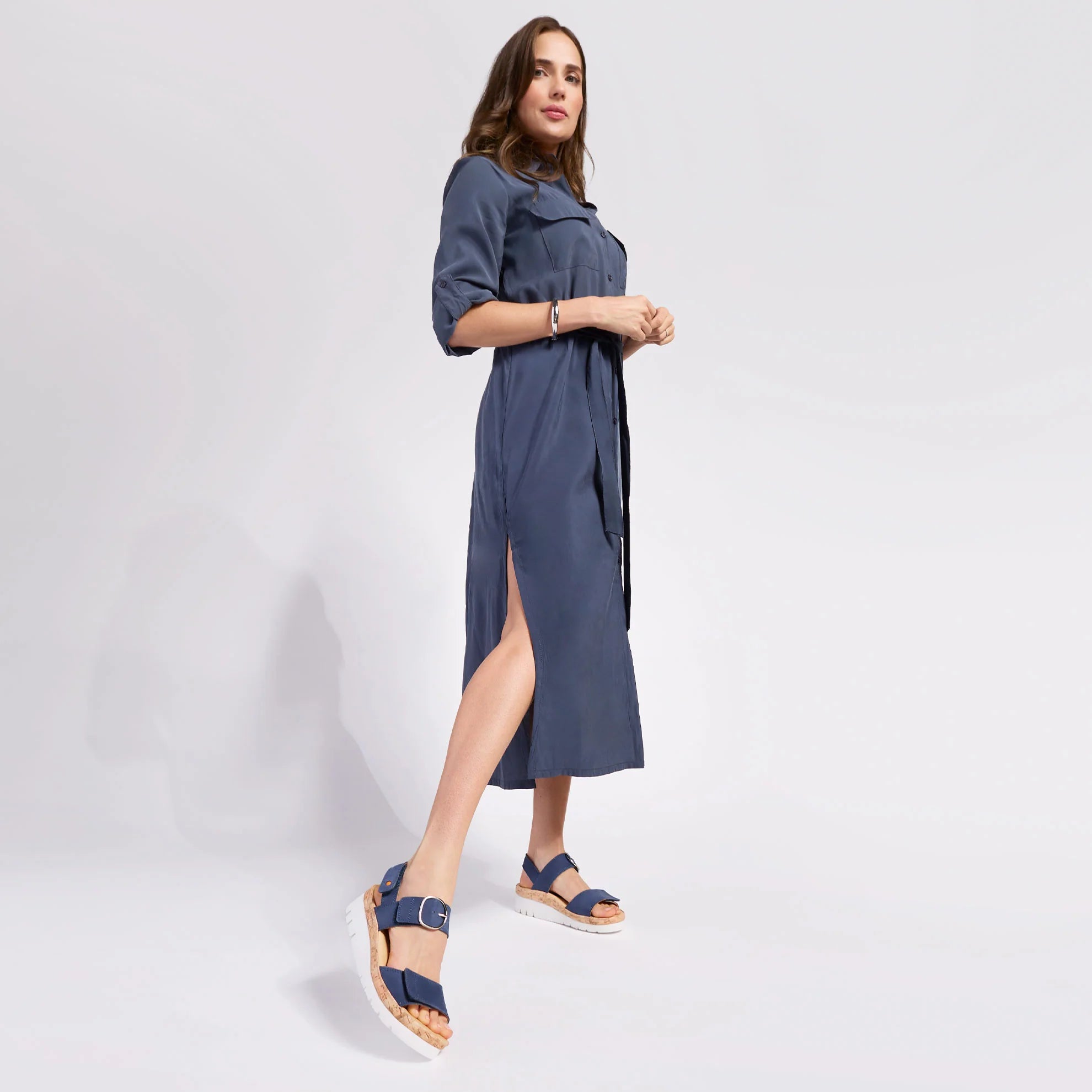 Woman wearing a blue dress with a slit on a white background