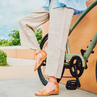 Person wearing tan sandals and beige pants sitting on a bicycle with a blurred background