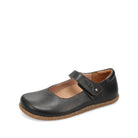 A black leather Mary Jane shoe with a hook-and-loop strap closure and a natural brown cork sole, shown from a side profile on a white background.