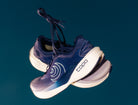 Navy running shoes with white soles on a dark blue background
