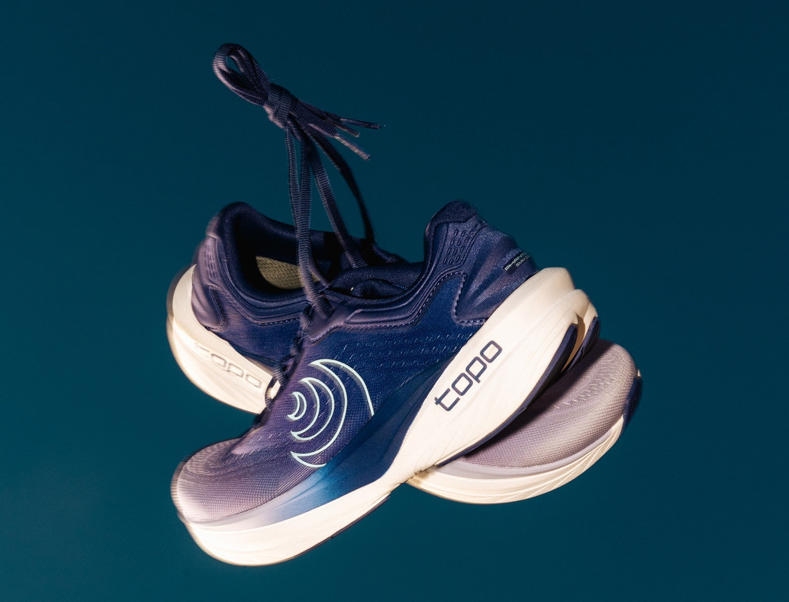 Navy running shoes with white soles on a dark blue background