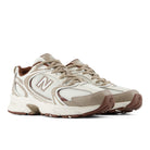 A pair of New Balance 530 running shoes in beige, white, and brown, shown from a three-quarters angle on a white background.