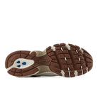 The outsole of a New Balance sneaker, showing a brown and beige tread pattern with blue accents on the heel, isolated on a white background.