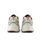 A pair of low-top athletic sneakers shown from the back, featuring a cream and beige mesh upper with brown accents on the collar, lining, and outsole.