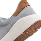 Close-up of a gray and brown sneaker with a white sole on a white background