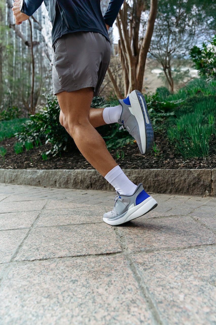Person running on a paved path with greenery in the background