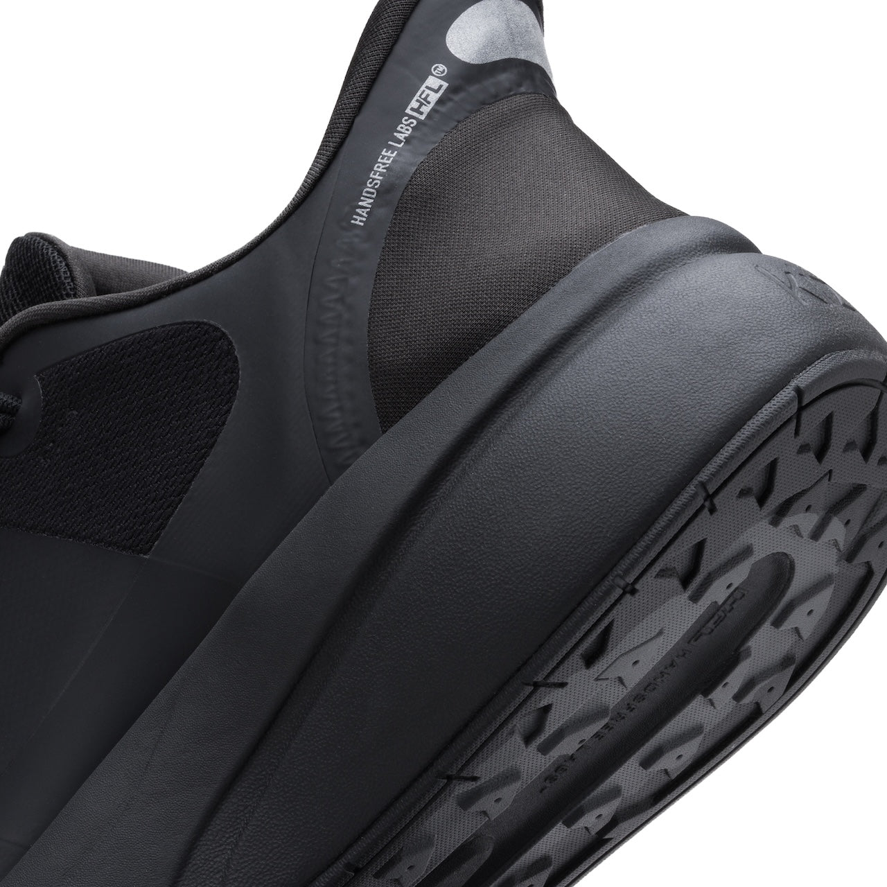 Close-up of a black athletic shoe showing the heel, collar lining, and textured outsole against a white background.