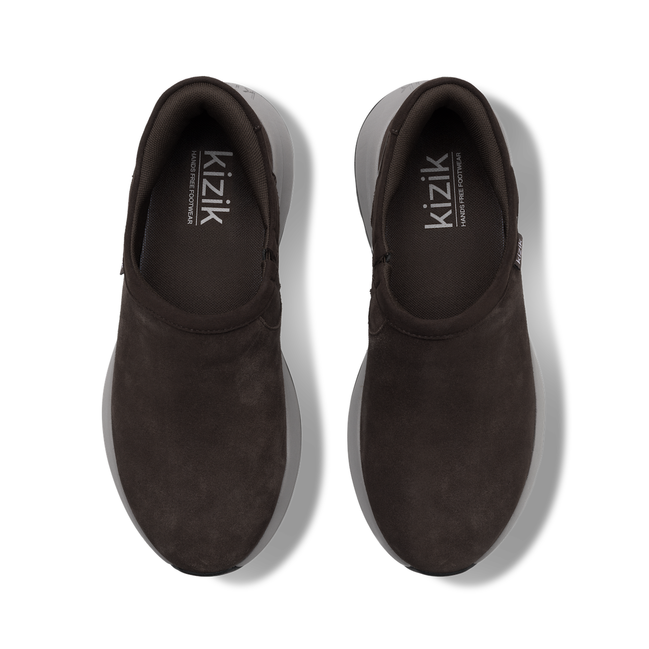 A pair of dark brown slip-on shoes with a suede-like finish, shown from a top-down view on a white background. The brand name 'kizik' is printed in white on the inner sole of each shoe.
