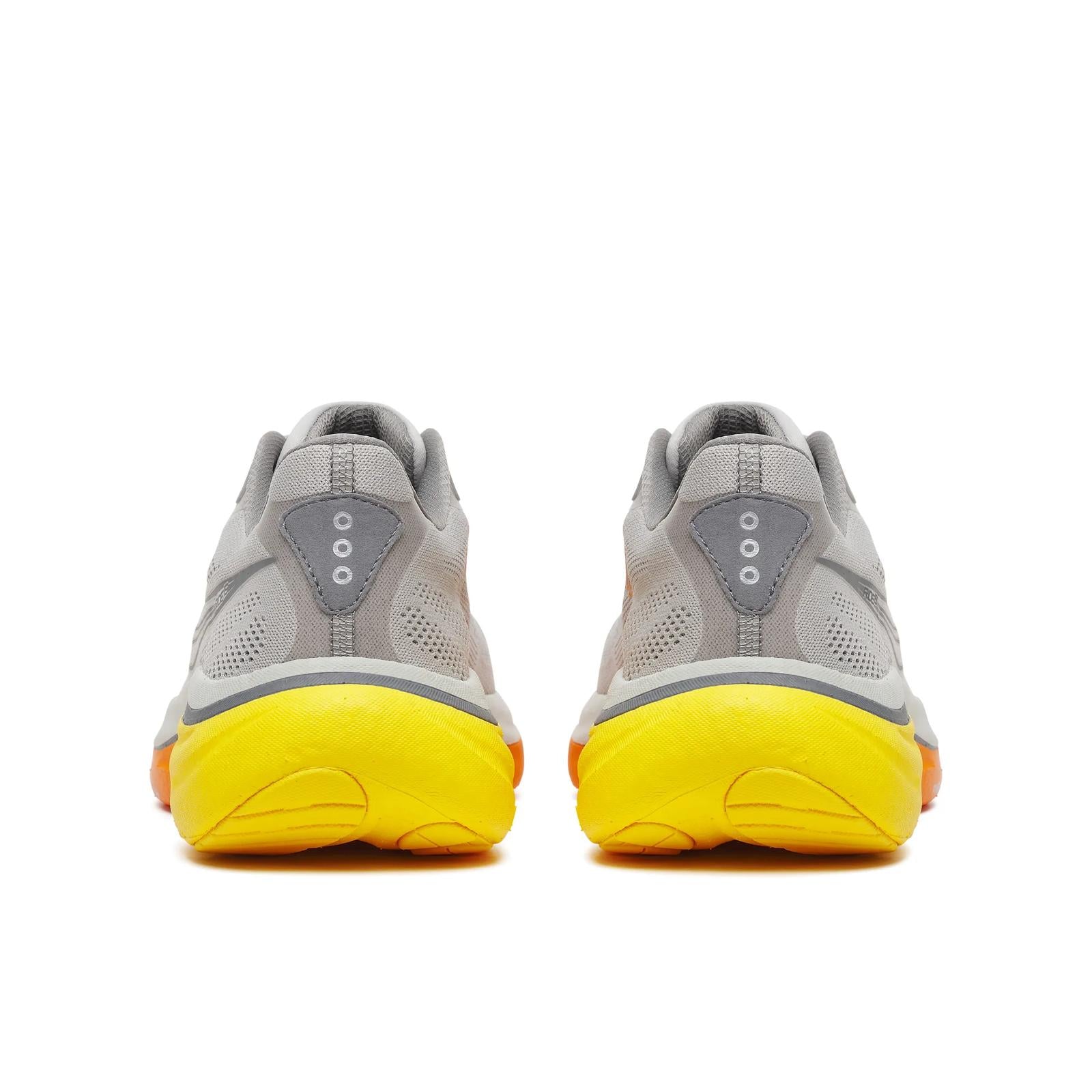 Gray athletic shoes with yellow soles on a white background