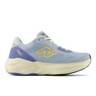 A New Balance sneaker in light blue with purple and yellow accents, featuring a thick cream-colored midsole and a yellow 'N' logo on the side.
