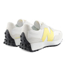 White sneakers with yellow accents and black soles on a white background