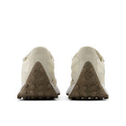 Pair of beige sneakers with brown sole on a white background
