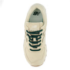 Beige sneaker with green laces on a white background