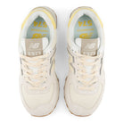 Pair of white sneakers with yellow accents on a white background