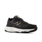 A black New Balance sneaker with a chunky white midsole and a textured gold 'N' logo on the side, shown against a plain white background.
